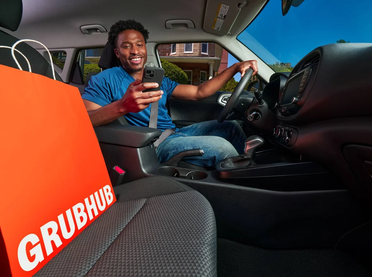 Courier inside a car with a Grubhub bag