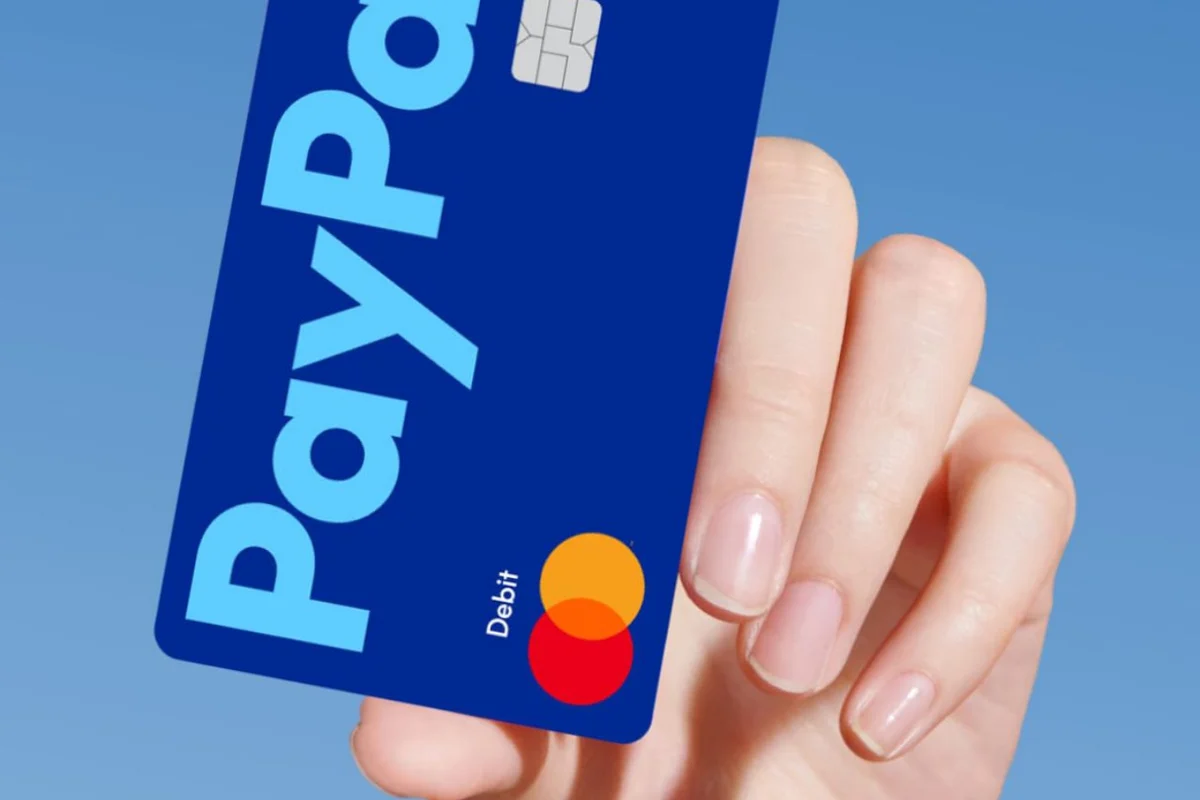 Hand holding a blue PayPal debit card