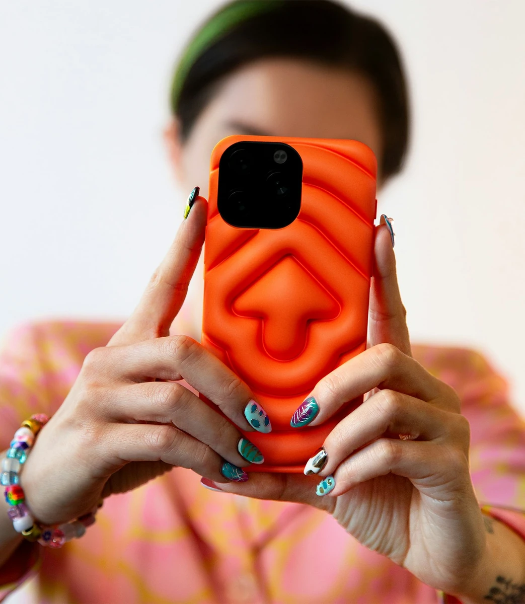 Person holding up an orange phone case with a sculpted Snoo