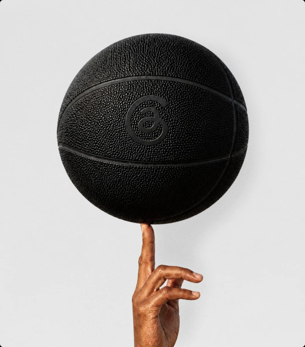 Black basketball embossed with the Threads @ symbol spinning on a finger