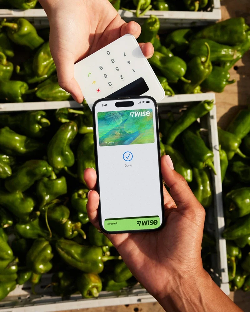 Hand holding a phone with the Wise app over limes